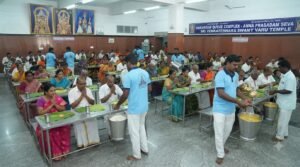 Pilgrims seated inside the Vaikuntam Queue Complex waiting compartments at Tirumala receiving free food and water.